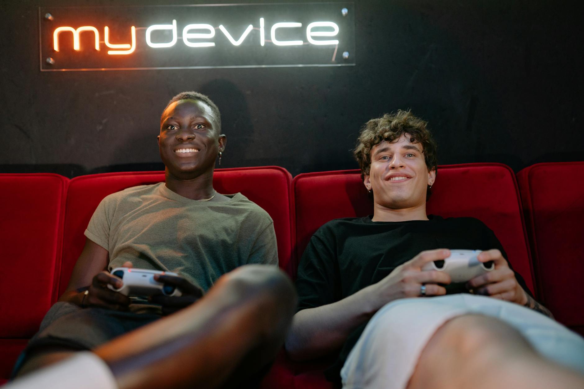 men sitting on red sofa playing video game