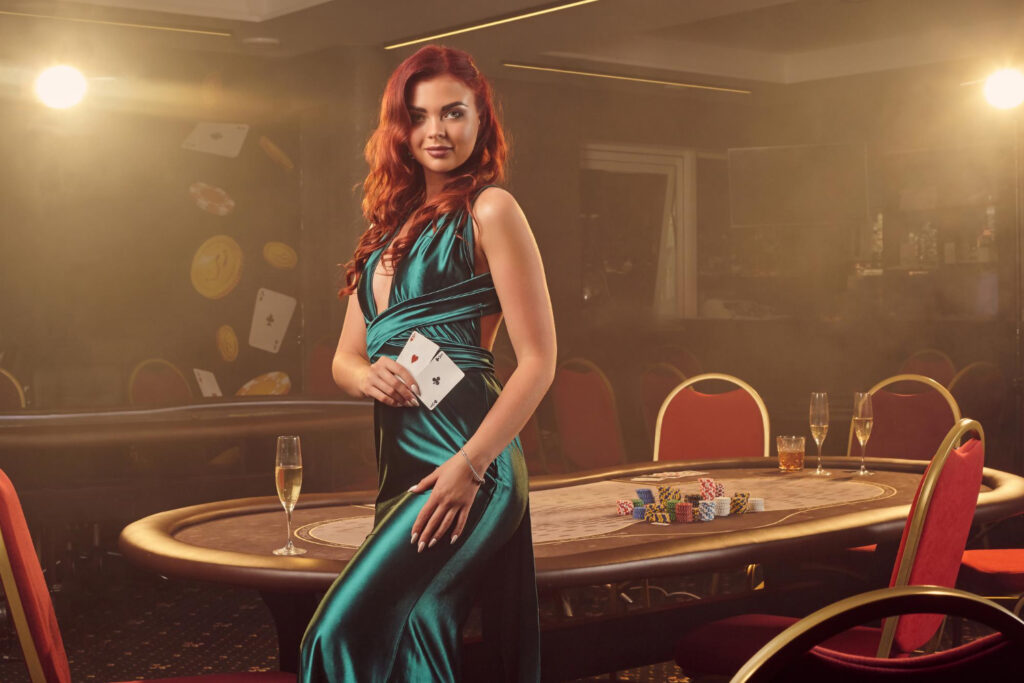 alluring redheaded girl long blue satin dress is smiling posing sideways with two aces her hand against poker table luxury casino passion cards chips alcohol win gambling it i 1 1024x683 1